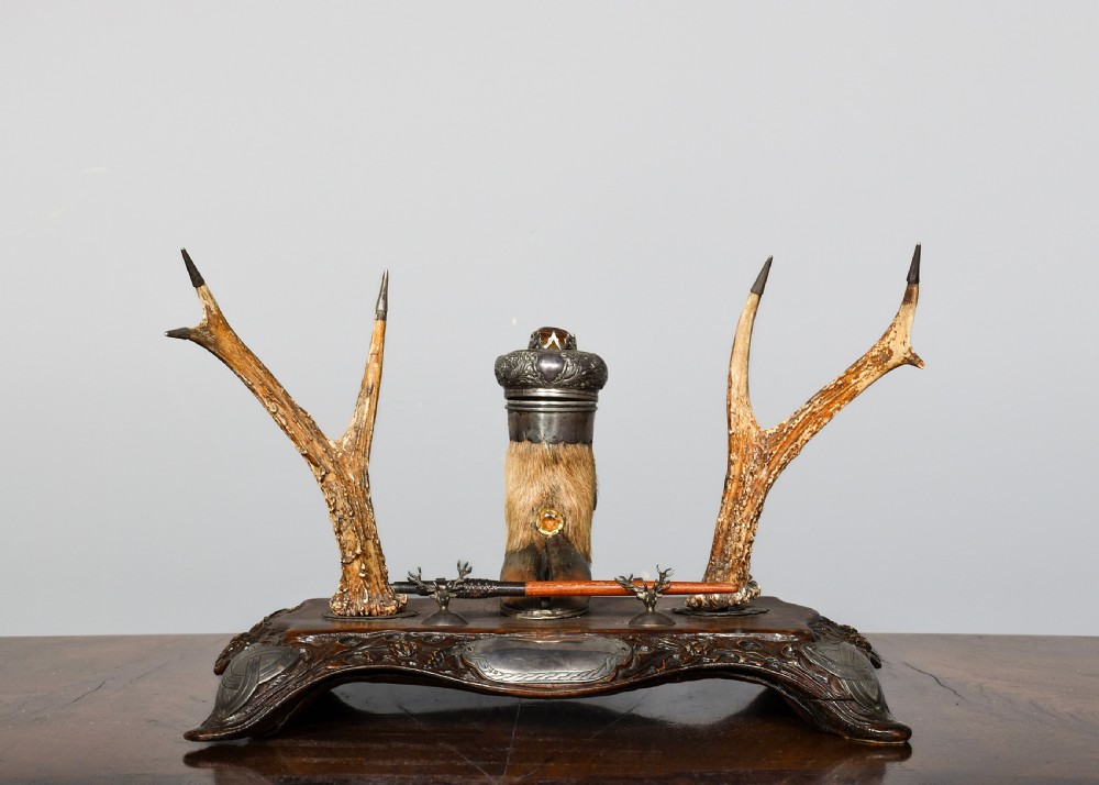 An antique Scottish carved oak desk stand featuring two upright stag antlers as pen rests and a central silver-mounted hoof inkwell.