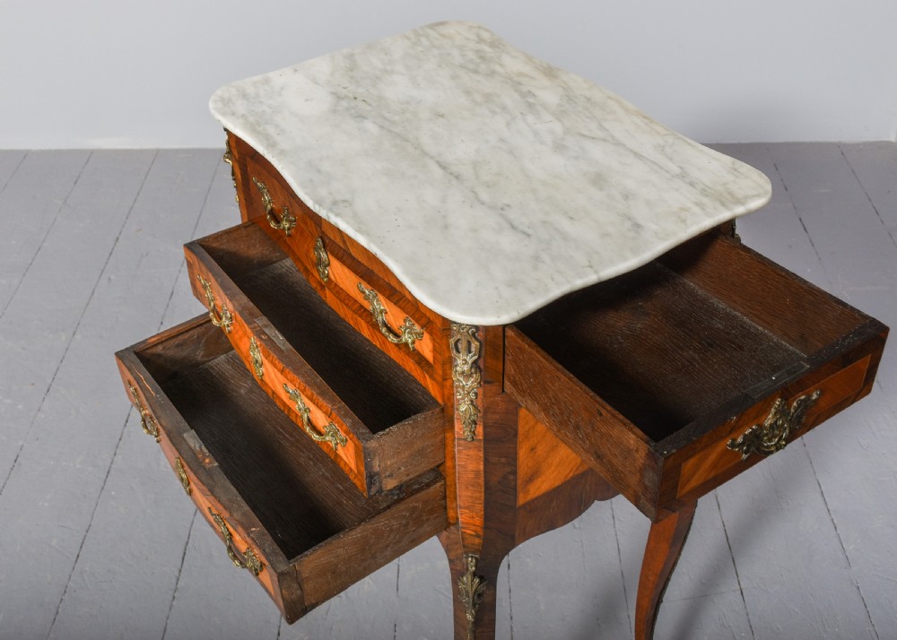 A French Louis XV style side table with a white marble top, three parquetry drawers, brass mounts, and slender cabriole legs. View III