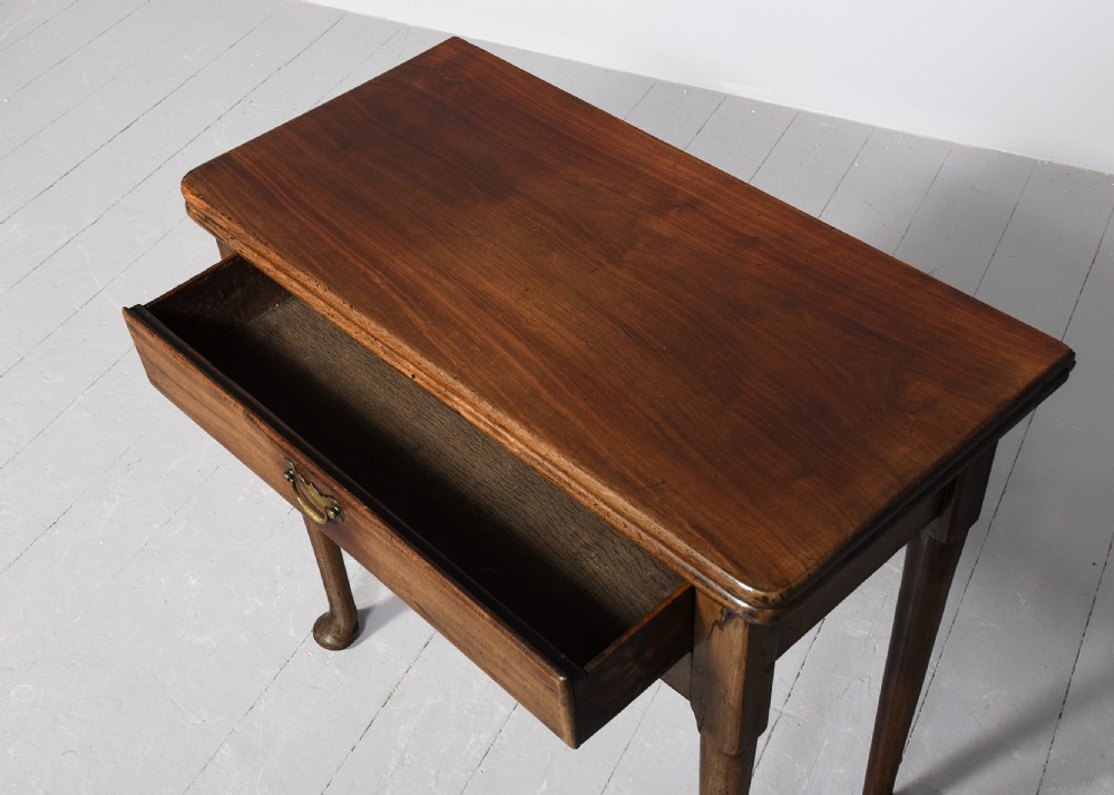 An 18th-century George II red walnut fold-over tea table with a single frieze drawer, brass brassware, shaped apron, and slender legs terminating in pad feet. View III