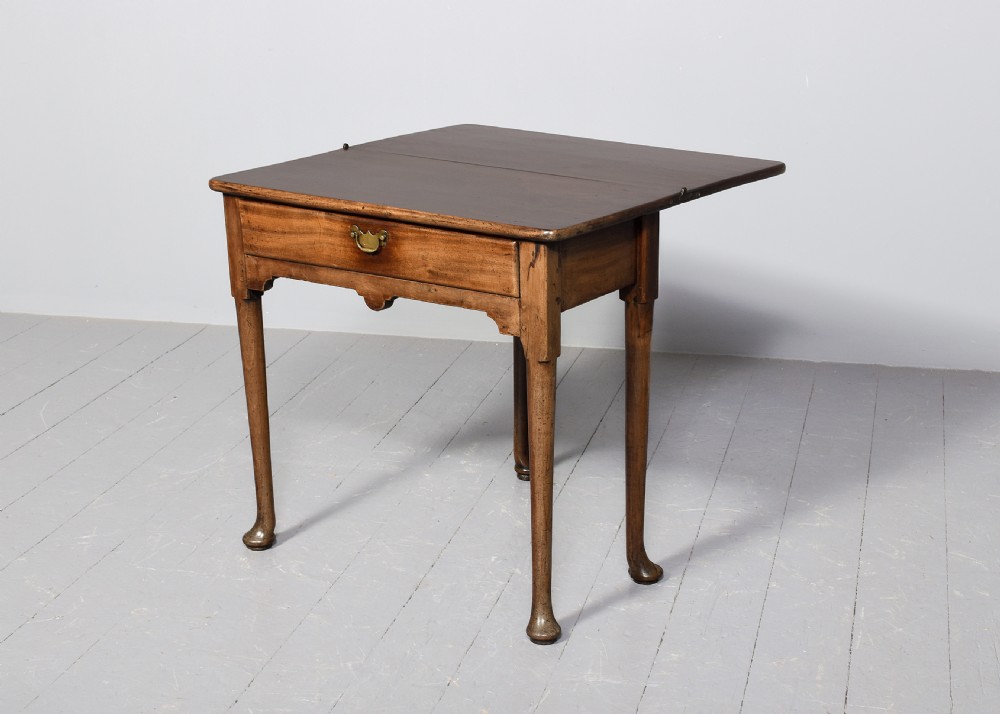 An 18th-century George II red walnut fold-over tea table with a single frieze drawer, brass brassware, shaped apron, and slender legs terminating in pad feet. View VII