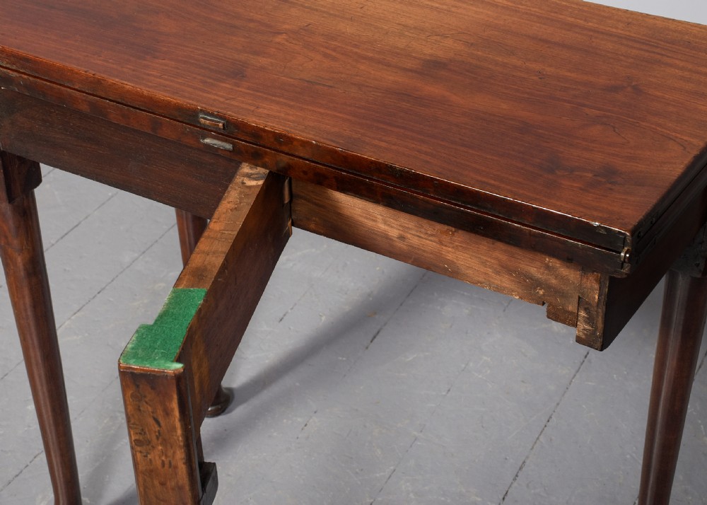 An 18th-century George II red walnut fold-over tea table with a single frieze drawer, brass brassware, shaped apron, and slender legs terminating in pad feet. View X