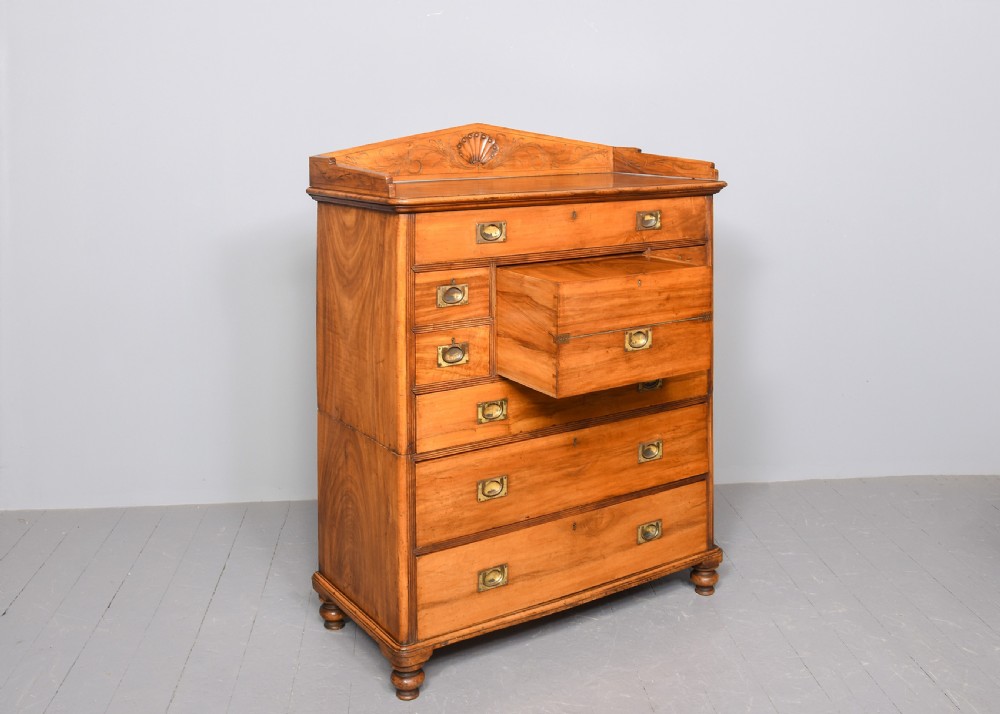 An antique two-part camphorwood military secretaire chest with recessed brass handles and a carved shell cresting. View II