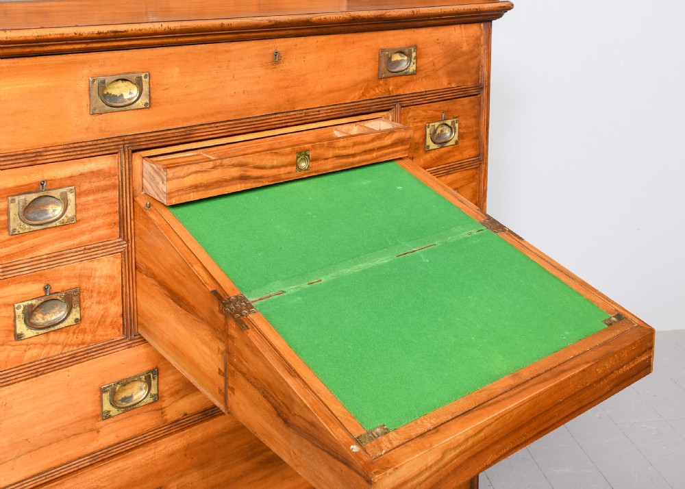 An antique two-part camphorwood military secretaire chest with recessed brass handles and a carved shell cresting. View V