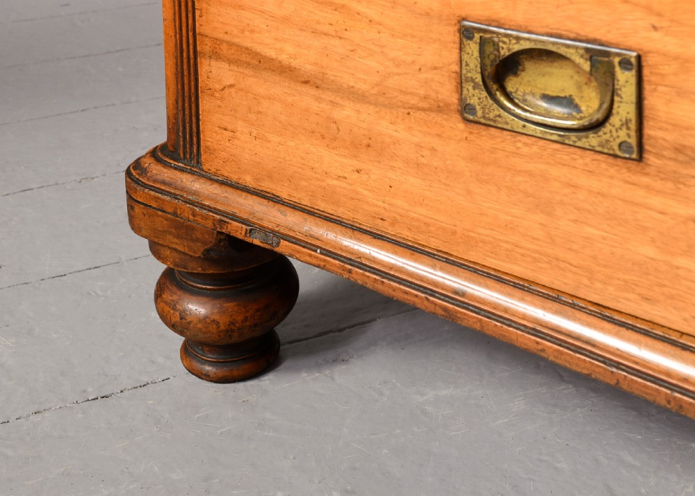 An antique two-part camphorwood military secretaire chest with recessed brass handles and a carved shell cresting. View X