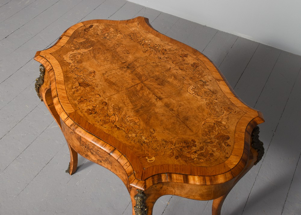 A Victorian burr walnut side table featuring a serpentine shaped top, gilt-bronze mounts, and carved cabriole legs. View III