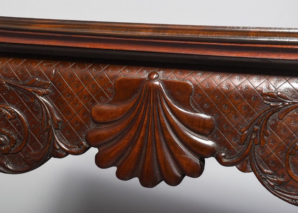 A dark carved mahogany console table in the Irish Chippendale style, featuring a deeply scalloped apron with central shell carving and cabriole legs. View III