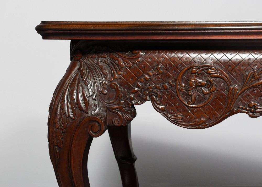 A dark carved mahogany console table in the Irish Chippendale style, featuring a deeply scalloped apron with central shell carving and cabriole legs. View IV