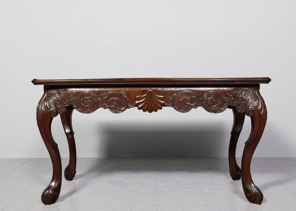 A dark carved mahogany console table in the Irish Chippendale style, featuring a deeply scalloped apron with central shell carving and cabriole legs. View VII