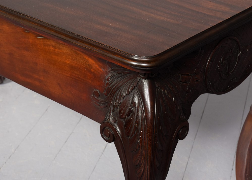 A dark carved mahogany console table in the Irish Chippendale style, featuring a deeply scalloped apron with central shell carving and cabriole legs. View IX