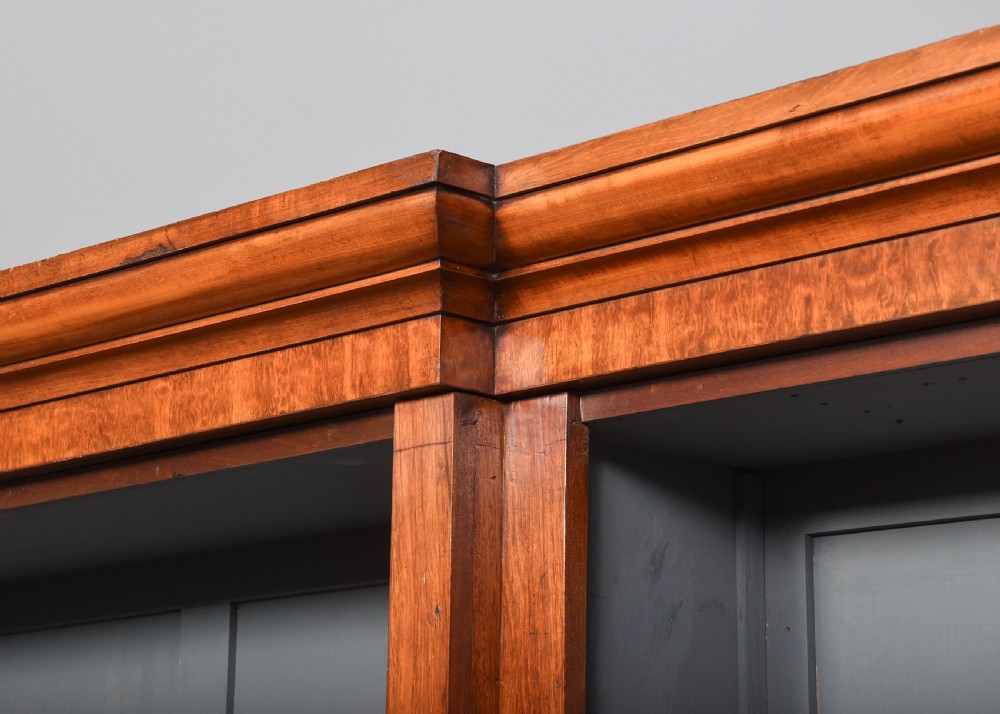 A large Victorian mahogany breakfront open bookcase featuring three sectioned compartments with adjustable shelves and a grey painted interior background. View III