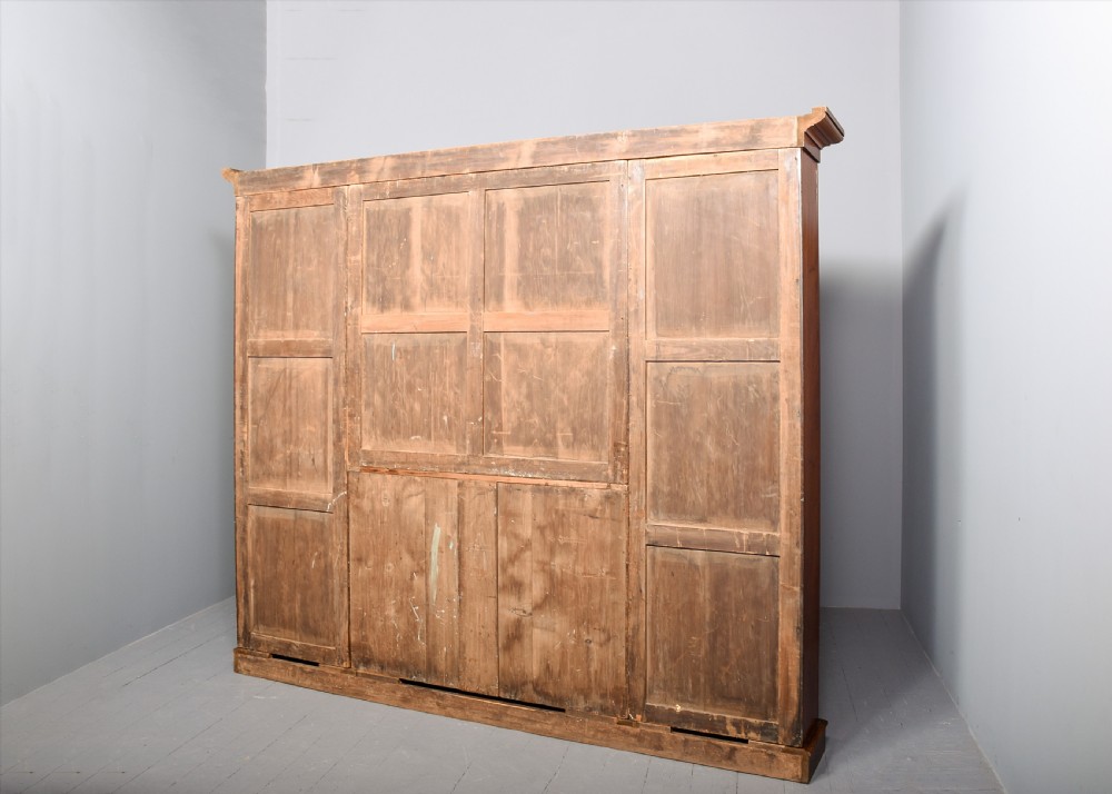 A large Victorian mahogany breakfront open bookcase featuring three sectioned compartments with adjustable shelves and a grey painted interior background. View IX