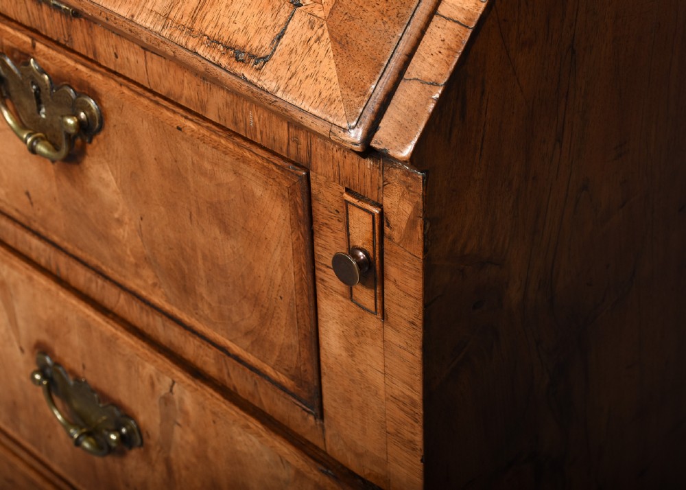 A George II walnut bureau bookcase featuring a broken arch pediment with finial, glazed upper doors, a fall-front desk, and lower drawers on bracket feet. View VIII