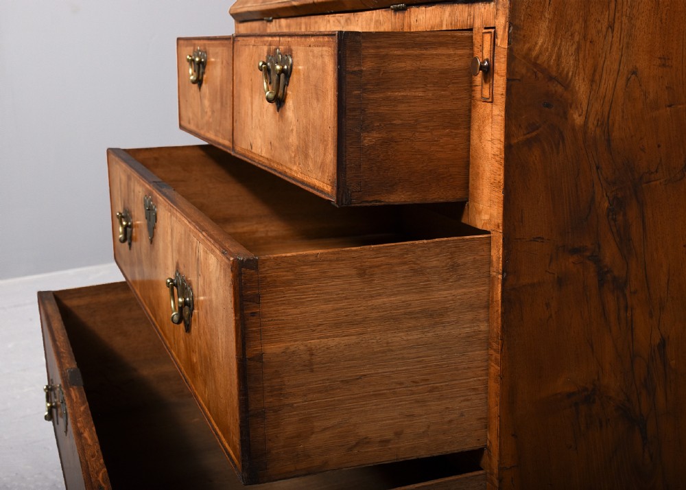 A George II walnut bureau bookcase featuring a broken arch pediment with finial, glazed upper doors, a fall-front desk, and lower drawers on bracket feet. View XII