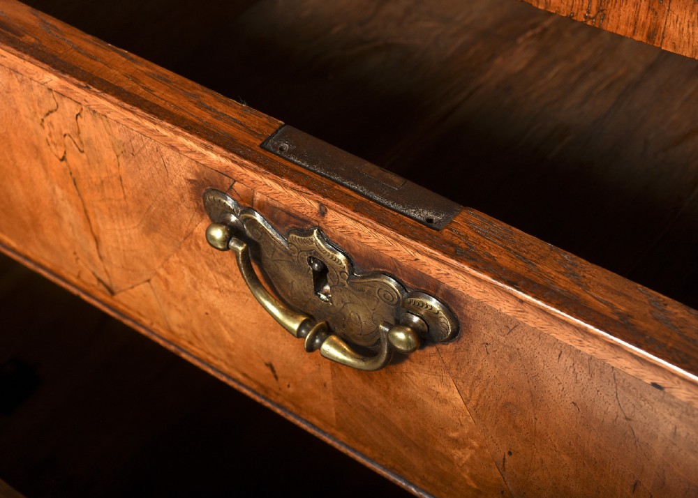 A George II walnut bureau bookcase featuring a broken arch pediment with finial, glazed upper doors, a fall-front desk, and lower drawers on bracket feet. View XIII