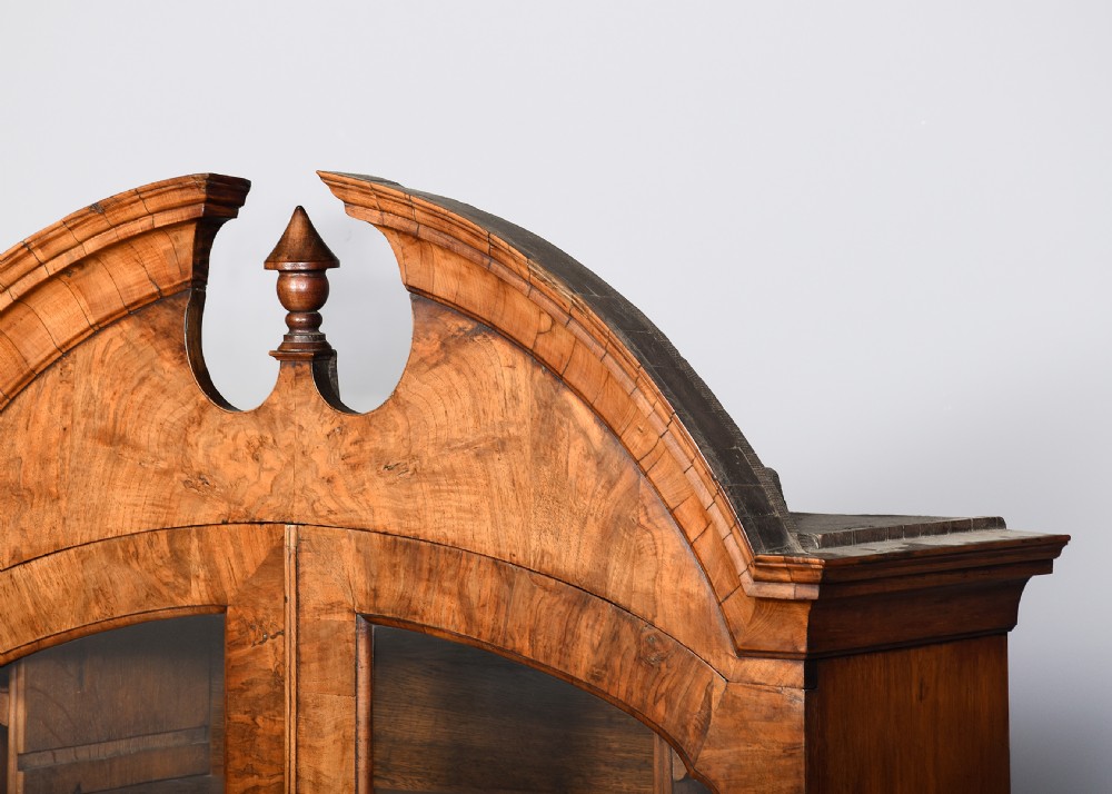A George II walnut bureau bookcase featuring a broken arch pediment with finial, glazed upper doors, a fall-front desk, and lower drawers on bracket feet. View XV