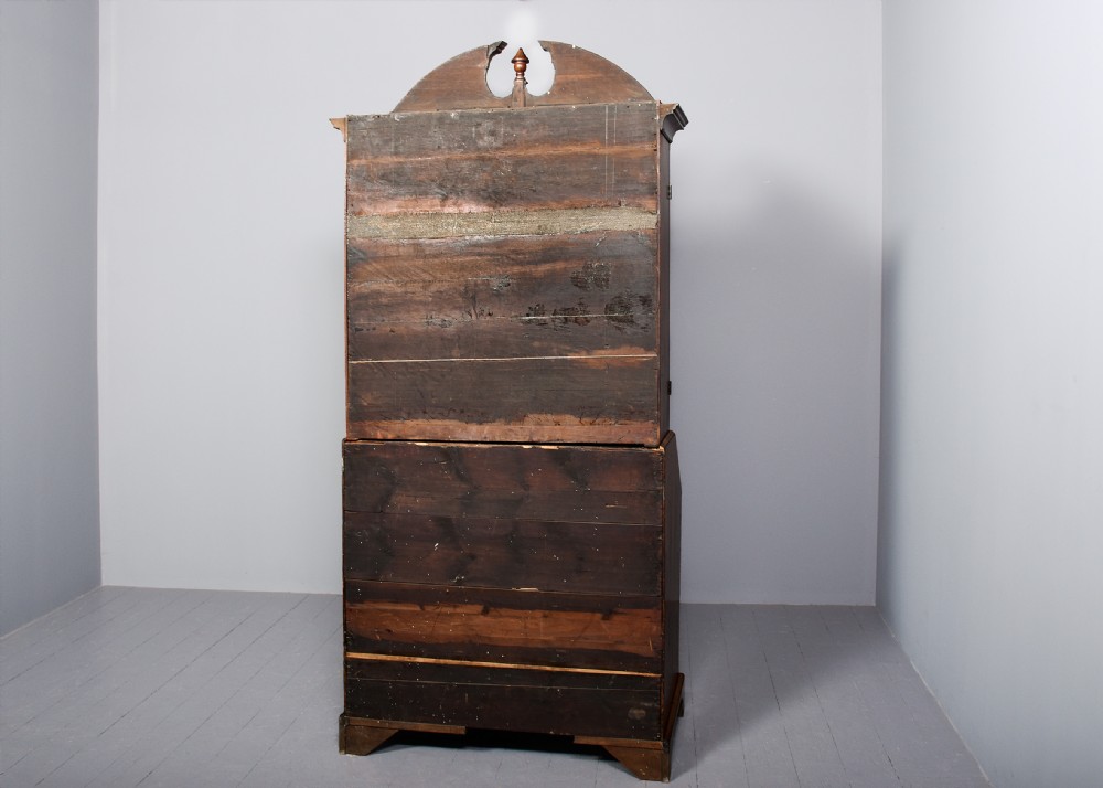 A George II walnut bureau bookcase featuring a broken arch pediment with finial, glazed upper doors, a fall-front desk, and lower drawers on bracket feet. View XVIII