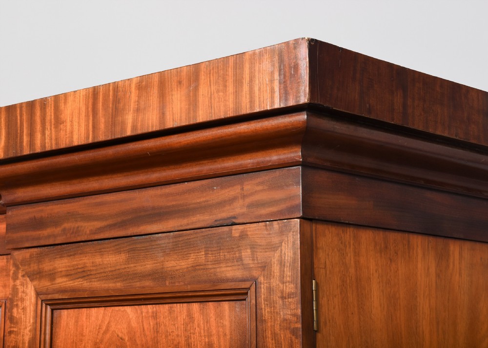 A George IV flame mahogany four-door wardrobe with a breakfront profile and moulded cornice. View II