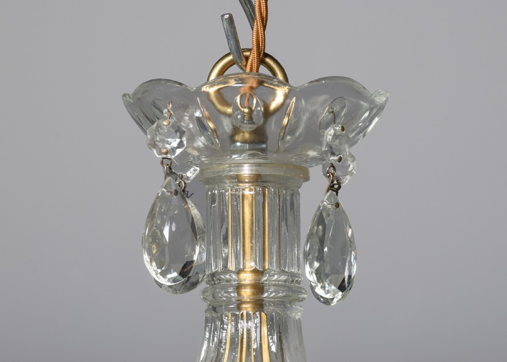 A multi-arm clear glass and cut crystal chandelier featuring hanging teardrop prisms, scalloped glass candle cups, and white candle sleeves. View II