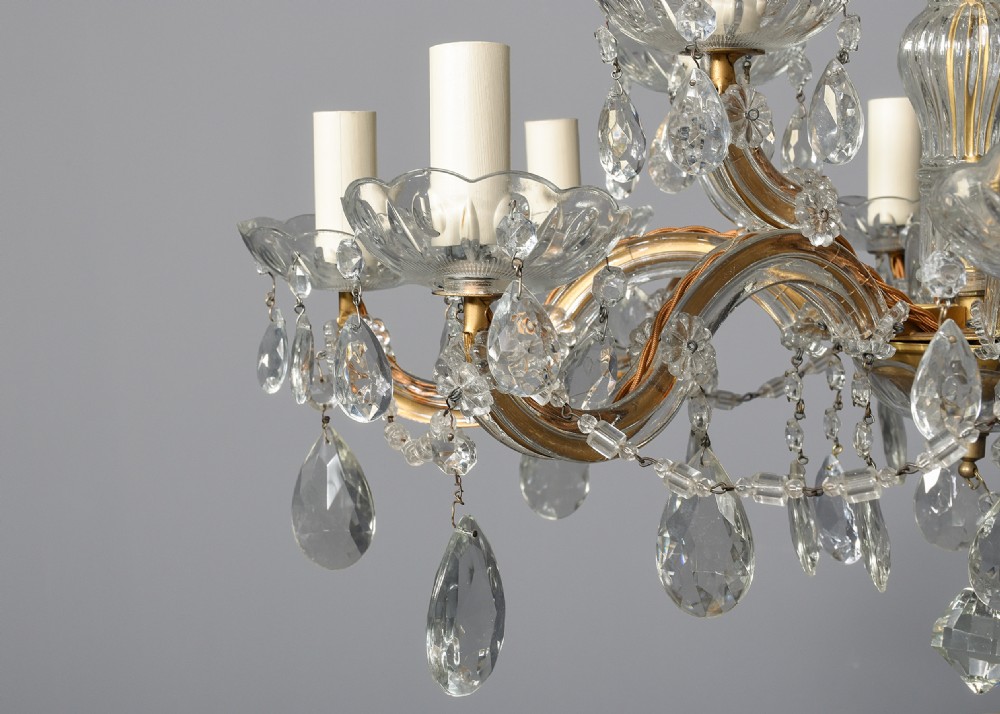 A multi-arm clear glass and cut crystal chandelier featuring hanging teardrop prisms, scalloped glass candle cups, and white candle sleeves. View III