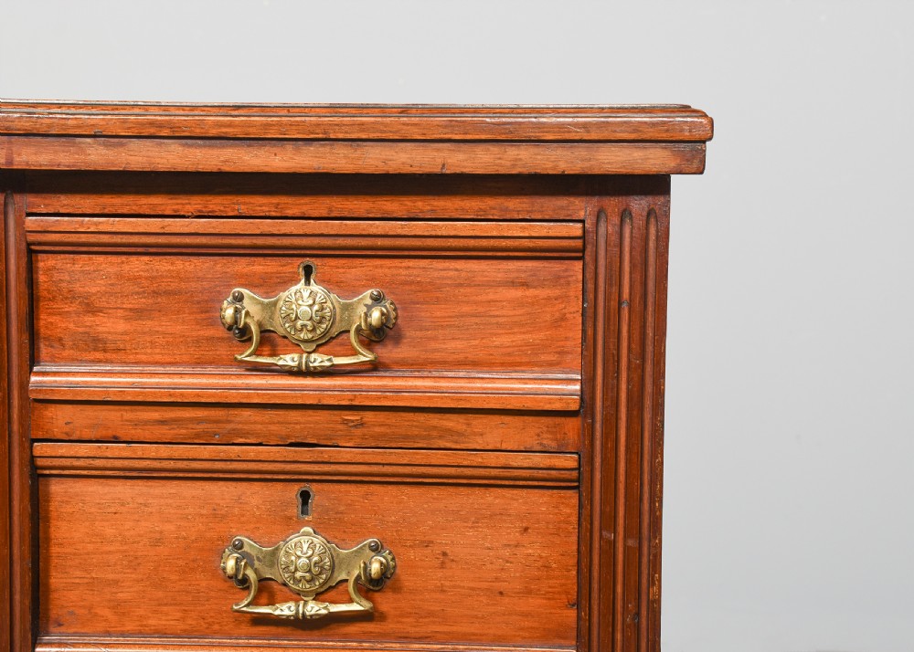 A pair of narrow late Victorian walnut bedside lockers with four drawers, brass drop handles, keyholes, and solid plinth bases. View VI