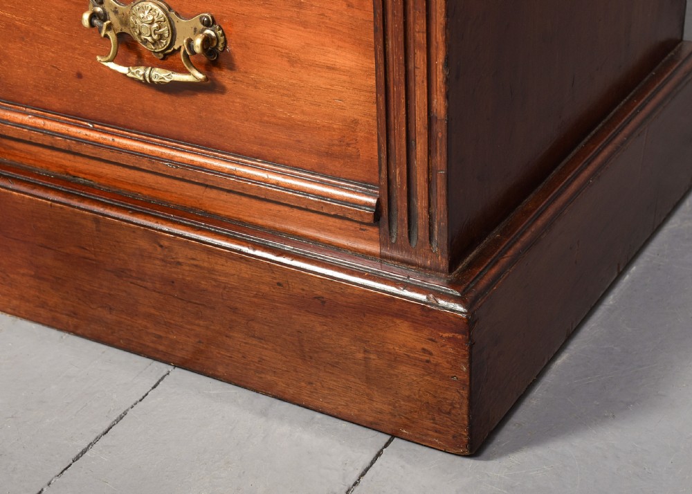 A pair of narrow late Victorian walnut bedside lockers with four drawers, brass drop handles, keyholes, and solid plinth bases. View VIII