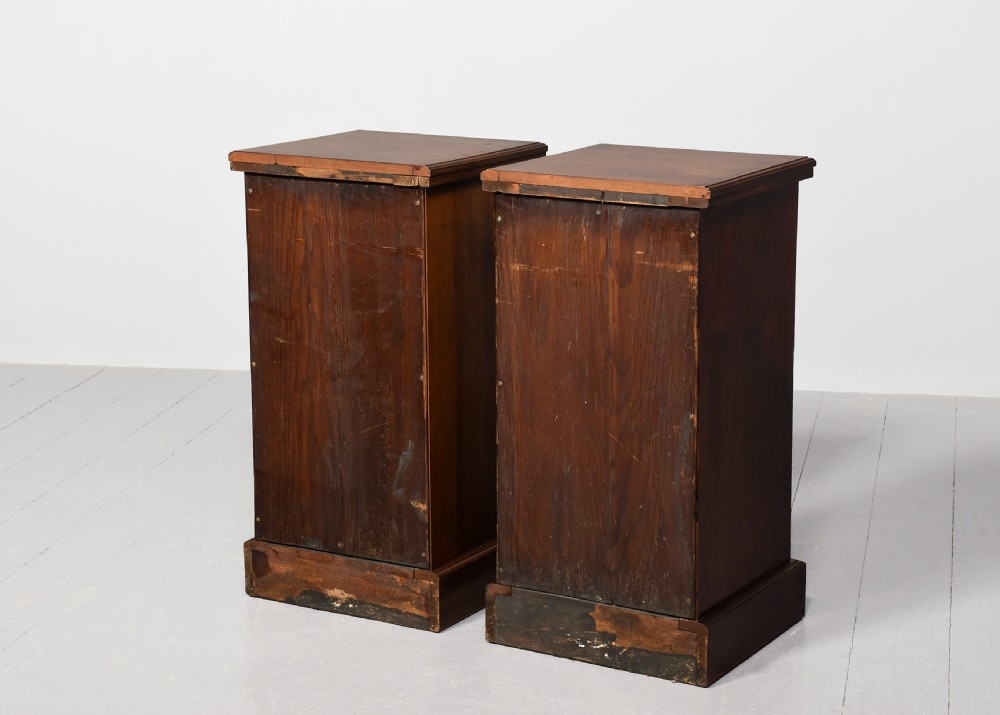 A pair of narrow late Victorian walnut bedside lockers with four drawers, brass drop handles, keyholes, and solid plinth bases. View IX