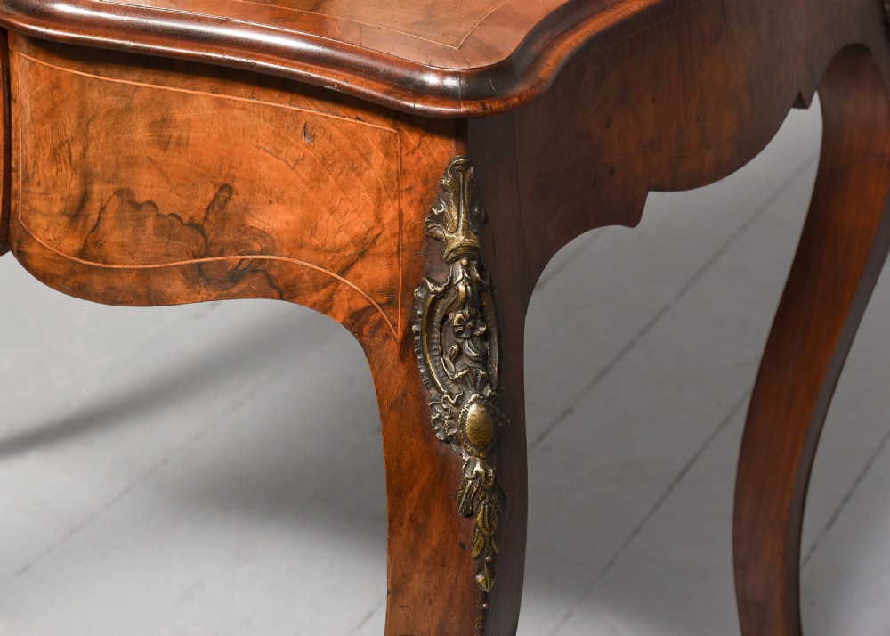 A Victorian figured walnut bonheur de jour writing desk featuring marquetry inlays, a mirrored central cabinet, brass gallery rail, and slender cabriole legs. View VI