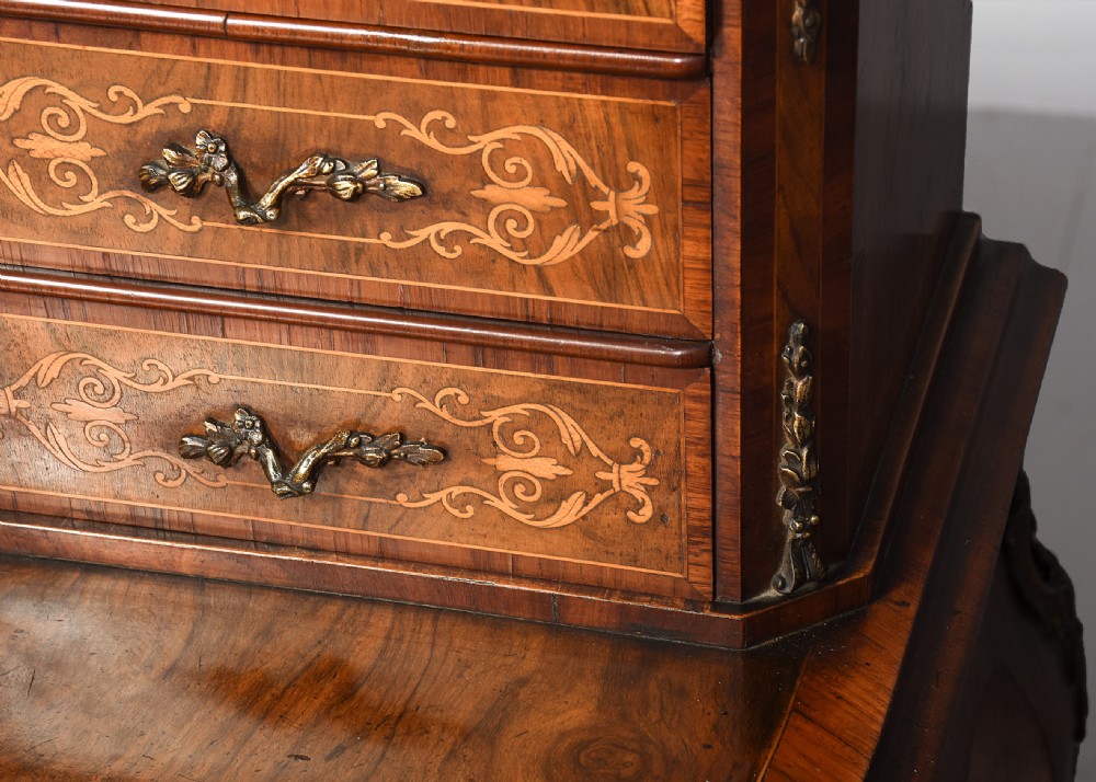 A Victorian figured walnut bonheur de jour writing desk featuring marquetry inlays, a mirrored central cabinet, brass gallery rail, and slender cabriole legs. View VII