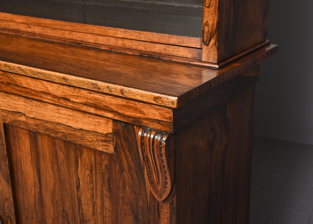 A two-part Regency rosewood bookcase featuring an open upper shelf area above a twin-door lower cupboard with carved corbels. View IX