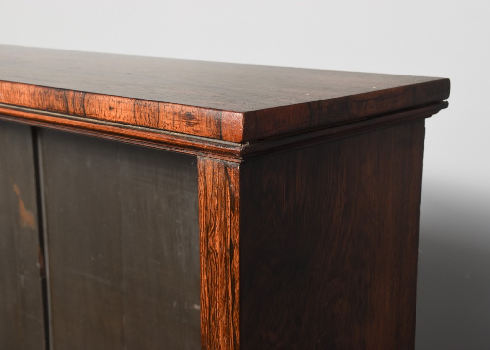 A two-part Regency rosewood bookcase featuring an open upper shelf area above a twin-door lower cupboard with carved corbels. View XI