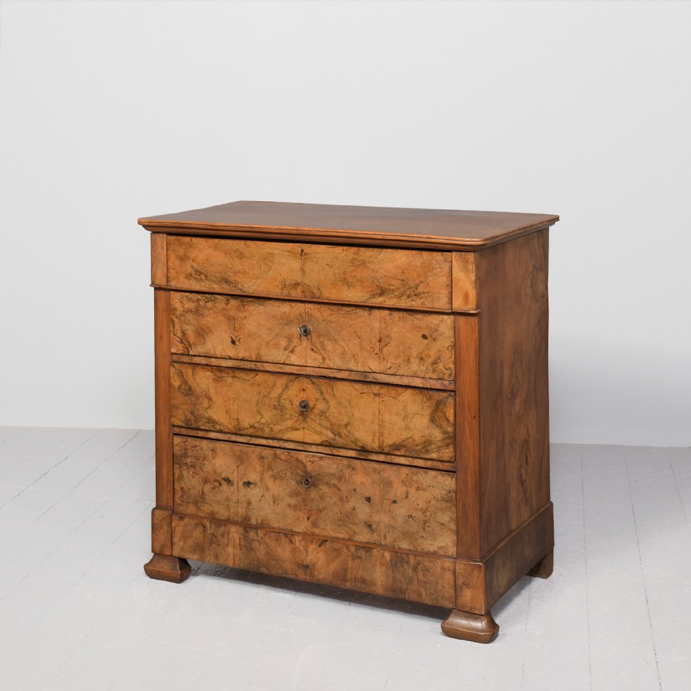A Biedermeier chest of drawers constructed from figured blonde walnut veneer with four drawers and block feet.