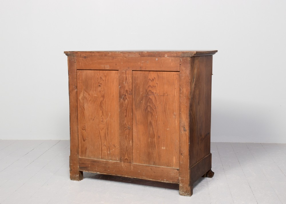 A Biedermeier chest of drawers constructed from figured blonde walnut veneer with four drawers and block feet. View VII