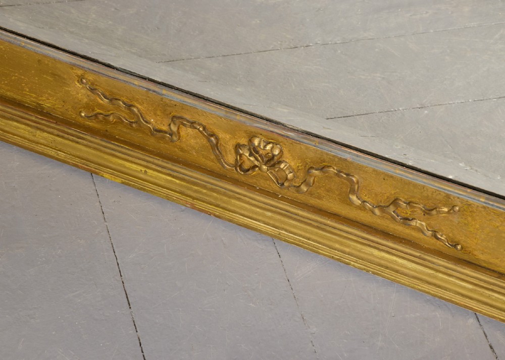 A large 19th-century Neoclassical giltwood overmantel mirror featuring classical column pilasters, ribbon festoon mouldings, and a heavy breakfront cornice. View V