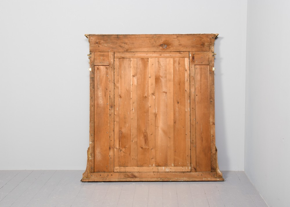 A large 19th-century Neoclassical giltwood overmantel mirror featuring classical column pilasters, ribbon festoon mouldings, and a heavy breakfront cornice. View VI