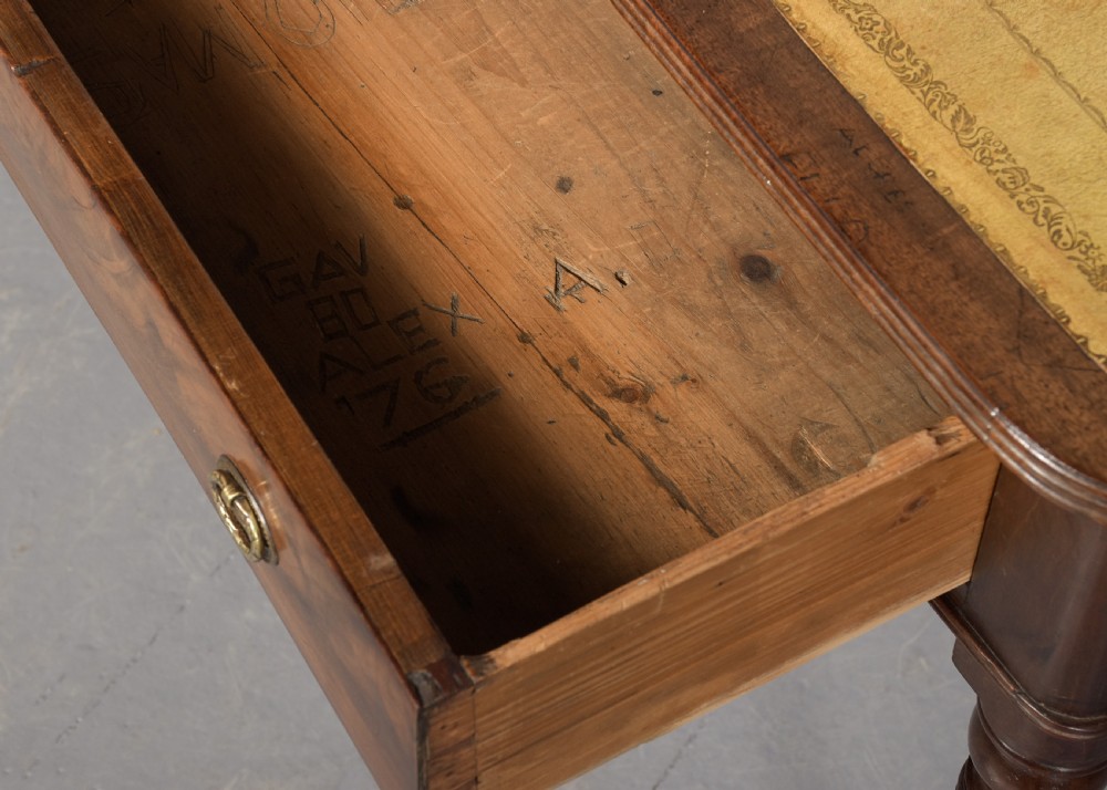 A George III mahogany library table featuring a tan leather writing surface, two frieze drawers with brass ring pulls, turned legs, and brass castors. View III