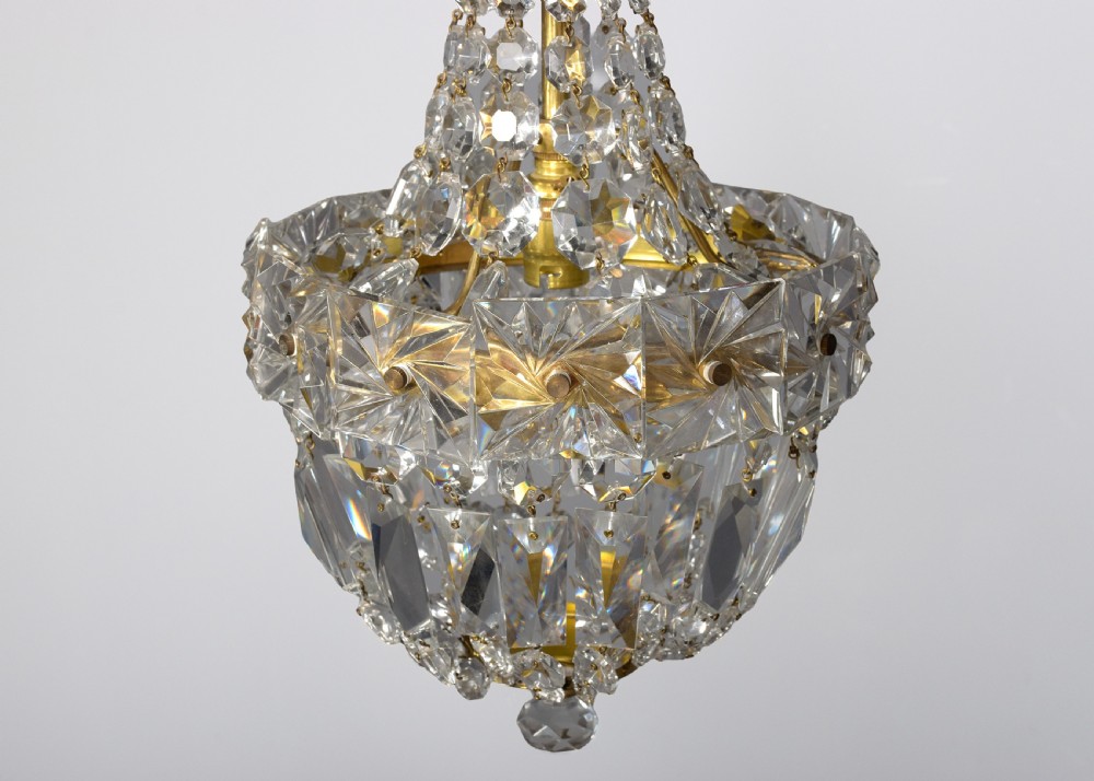 A pair of brass and cut crystal pendant light fittings featuring faceted glass droplets suspended from brass chains. View V