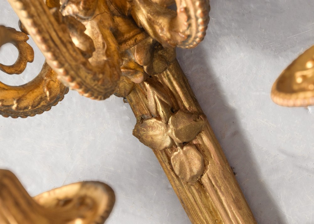 A set of four gilded three-arm wall sconces featuring neoclassical ribbon bow tops and scrolling leaf motifs. View XIV