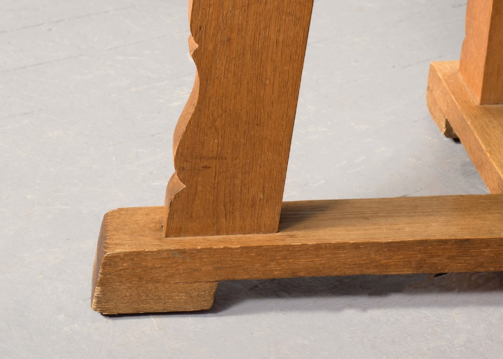 A circular solid oak dining table with a cross-shaped cruciform base and natural wood grain finish. View III