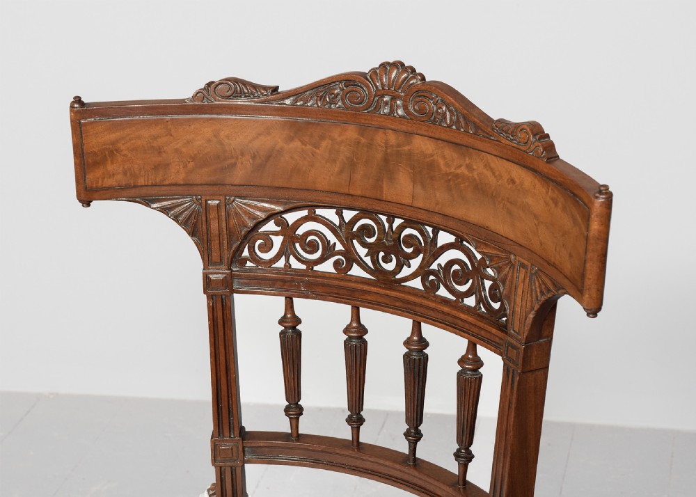 A carved mahogany side chair featuring a wide curved crest rail, pierced fretwork back, cushioned cane seat, and reeded front legs. View II