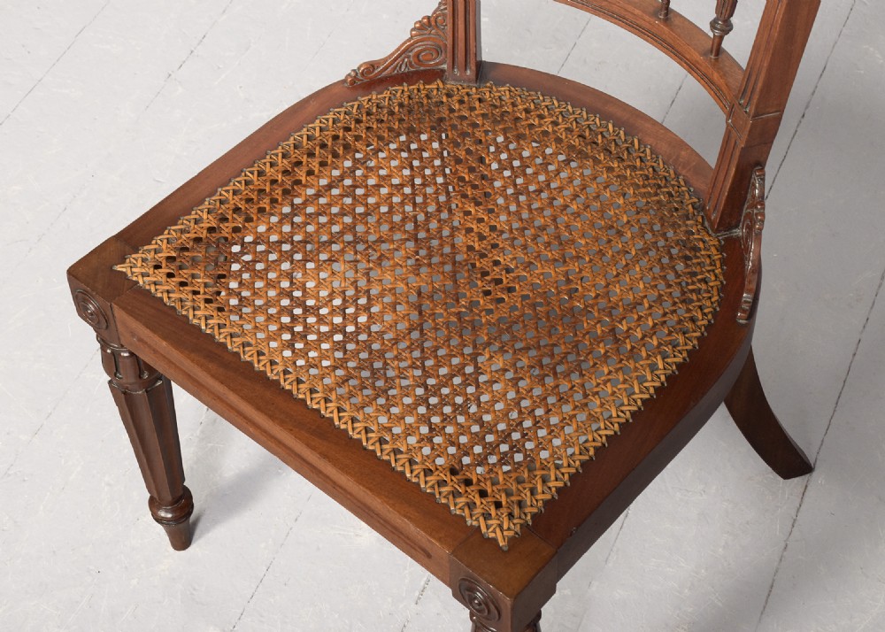 A carved mahogany side chair featuring a wide curved crest rail, pierced fretwork back, cushioned cane seat, and reeded front legs. View VIII