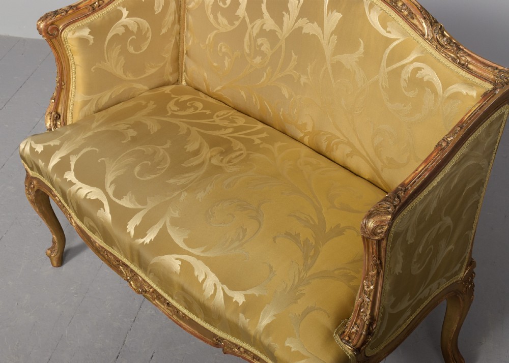 A French Louis XV style giltwood canape featuring carved floral motifs, cabriole legs, and gold floral damask upholstery. View III