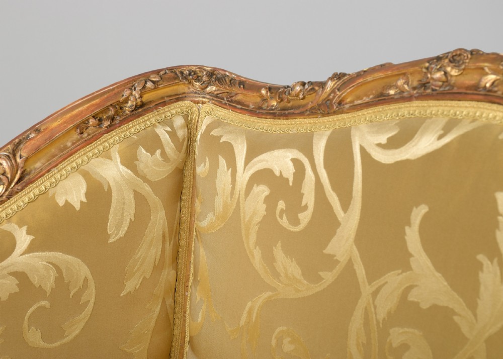 A French Louis XV style giltwood canape featuring carved floral motifs, cabriole legs, and gold floral damask upholstery. View V
