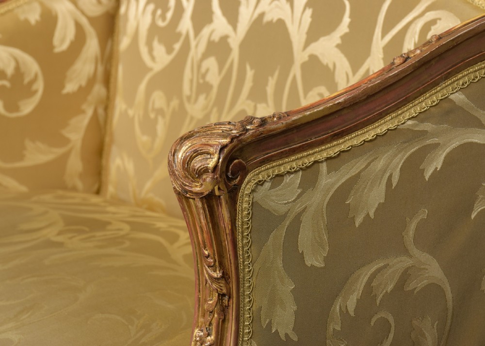 A French Louis XV style giltwood canape featuring carved floral motifs, cabriole legs, and gold floral damask upholstery. View VI