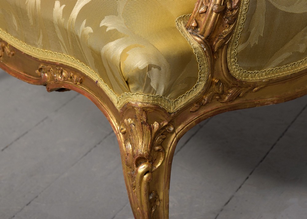 A French Louis XV style giltwood canape featuring carved floral motifs, cabriole legs, and gold floral damask upholstery. View VII