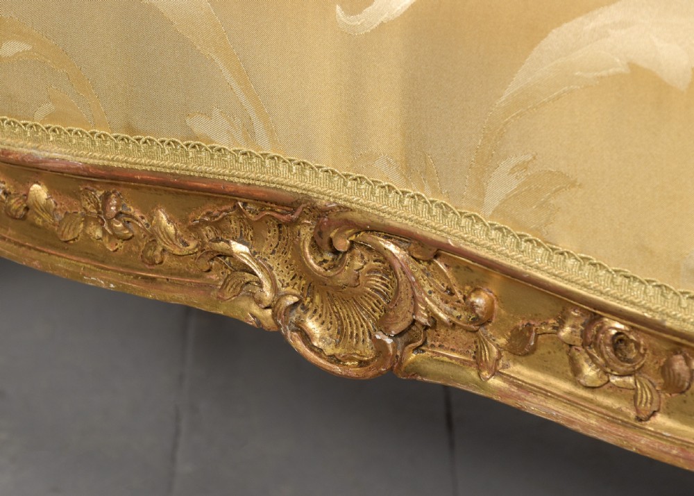 A French Louis XV style giltwood canape featuring carved floral motifs, cabriole legs, and gold floral damask upholstery. View IX