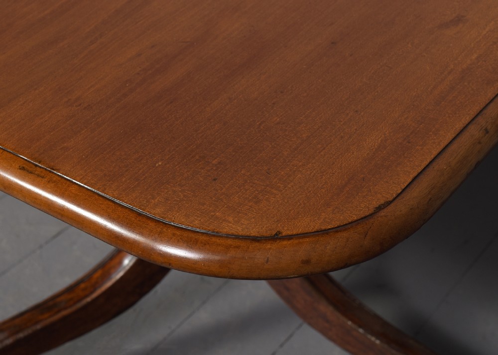 A George IV mahogany twin pillar extendable dining table with a central leaf, supported on turned columns and splayed legs with brass castors. View IV