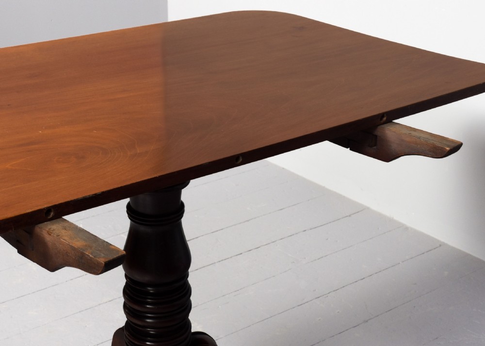 A George IV mahogany twin pillar extendable dining table with a central leaf, supported on turned columns and splayed legs with brass castors. View VIII