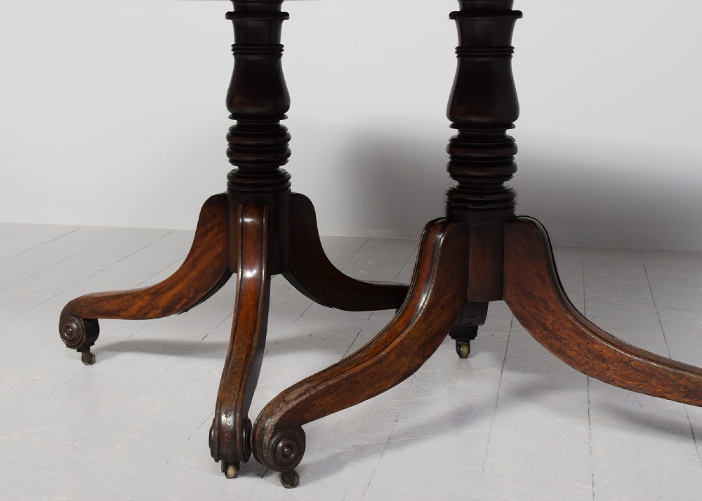 A George IV mahogany twin pillar extendable dining table with a central leaf, supported on turned columns and splayed legs with brass castors. View IX