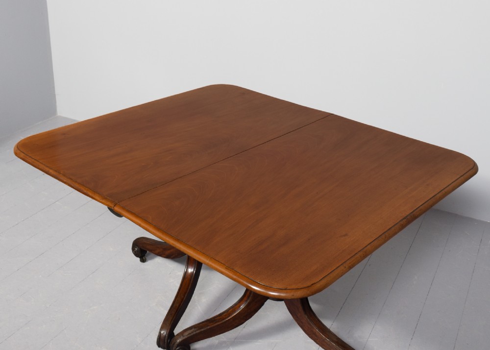 A George IV mahogany twin pillar extendable dining table with a central leaf, supported on turned columns and splayed legs with brass castors. View X