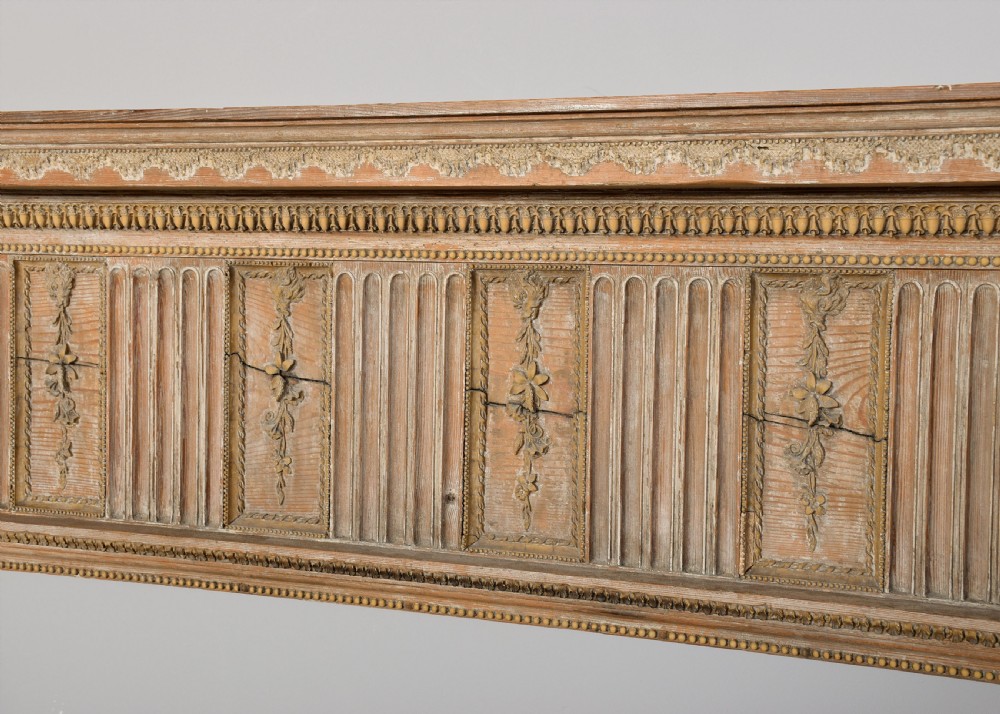 A George III carved pine and gesso fireplace surround featuring fluted jambs, classical urn motifs, and a detailed frieze. View III